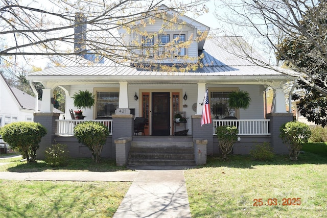 view of front of property with metal roof, a porch, and a front lawn