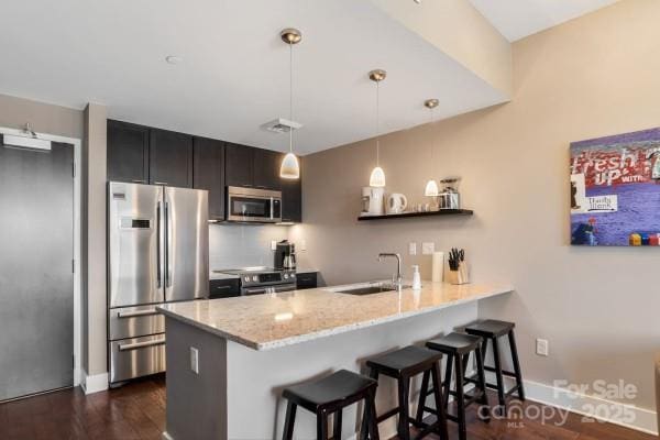 45 Asheland Ave Unit 500, Asheville, NC 28801 - kitchen with a breakfast bar area, a sink, light stone counters, a peninsula, and appliances with stainless steel finishes