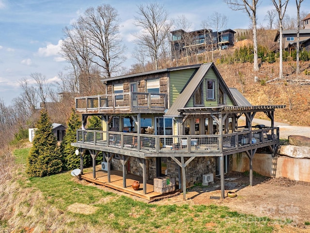 back of house featuring stone siding, metal roof, a wooden deck, and a lawn