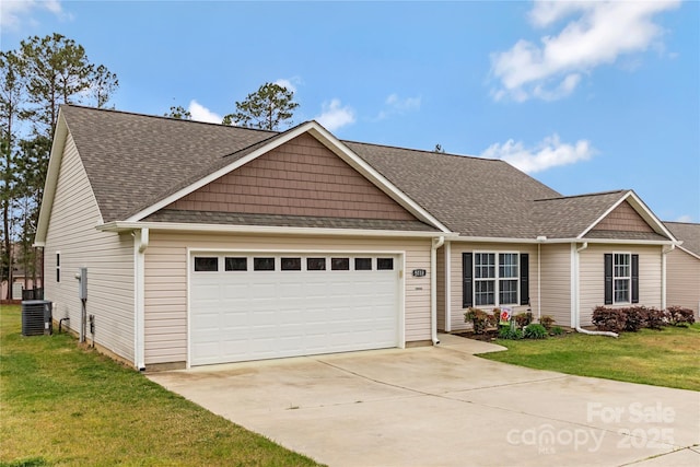 view of front of house featuring an attached garage, a front yard, roof with shingles, driveway, and cooling unit
