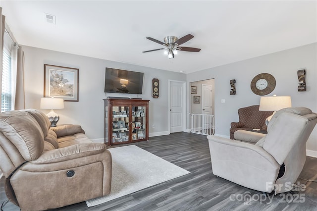 living room with dark wood-type flooring, visible vents, ceiling fan, and baseboards