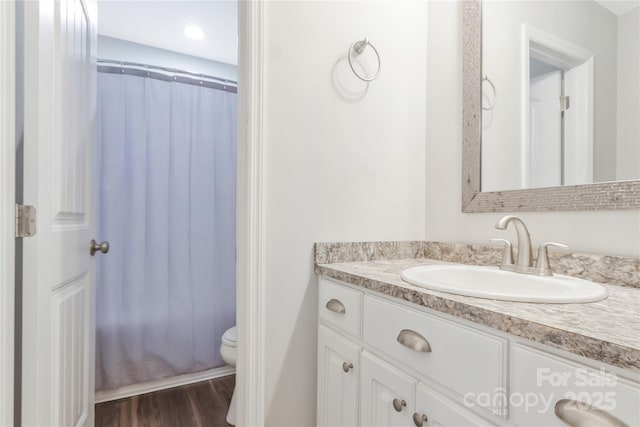 bathroom with toilet, a shower with shower curtain, vanity, and wood finished floors