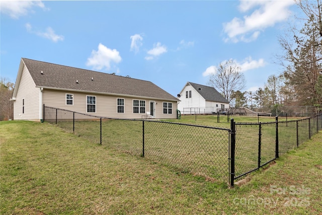 back of house featuring a shingled roof, fence, and a lawn