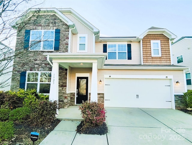 craftsman-style home with stone siding, a porch, driveway, and a garage