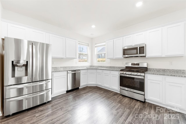 kitchen with dark wood-type flooring, white cabinetry, stainless steel appliances, and light stone counters