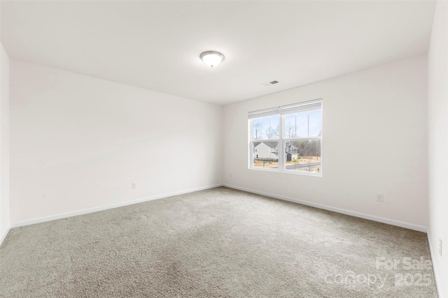 spare room featuring carpet flooring, baseboards, and visible vents