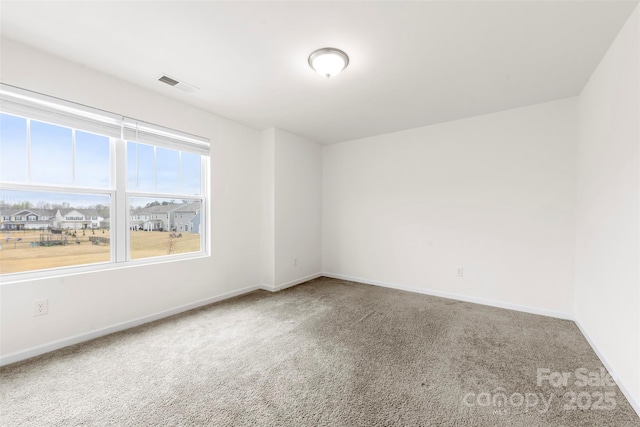 empty room with carpet flooring, baseboards, and visible vents