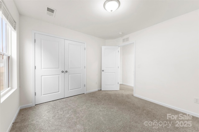 unfurnished bedroom featuring baseboards, visible vents, a closet, and carpet floors