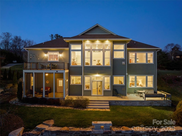 rear view of house featuring a balcony, a lawn, a sunroom, and a patio