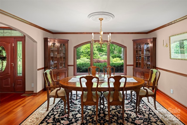 421 N Boundary Rd, Mill Spring, NC 28756 - dining space featuring light wood finished floors, arched walkways, a chandelier, crown molding, and baseboards