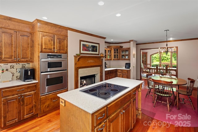421 N Boundary Rd, Mill Spring, NC 28756 - kitchen featuring double oven, black electric cooktop, light wood finished floors, ornamental molding, and brown cabinets