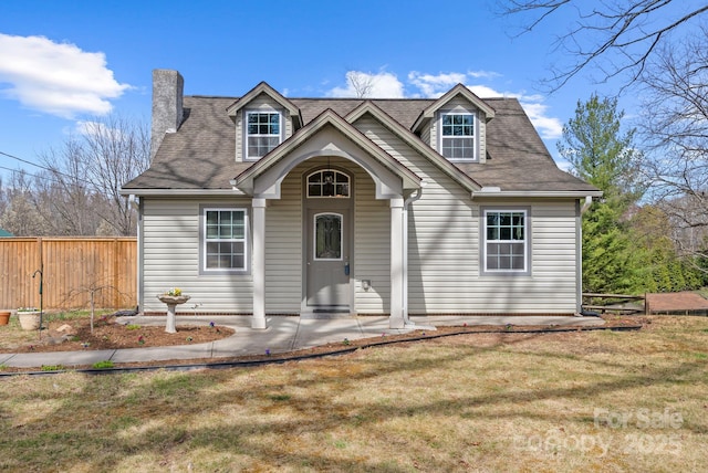 new england style home with a chimney, fence, a front yard, and a patio area