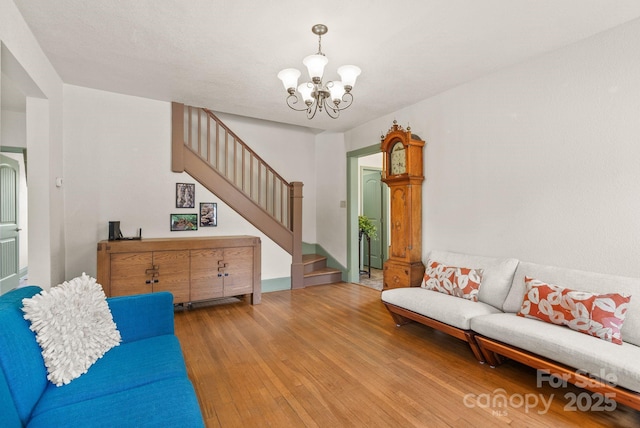 living area featuring wood-type flooring, an inviting chandelier, and stairs