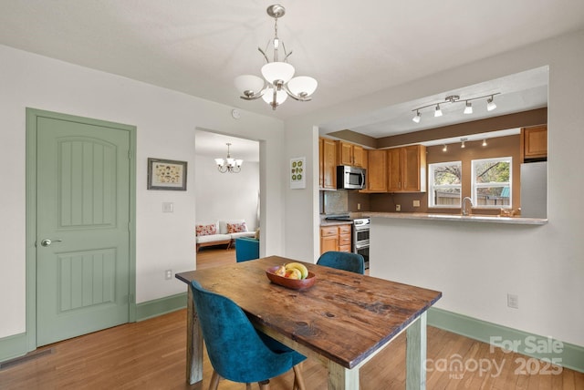 dining room featuring baseboards, light wood-style flooring, and a chandelier