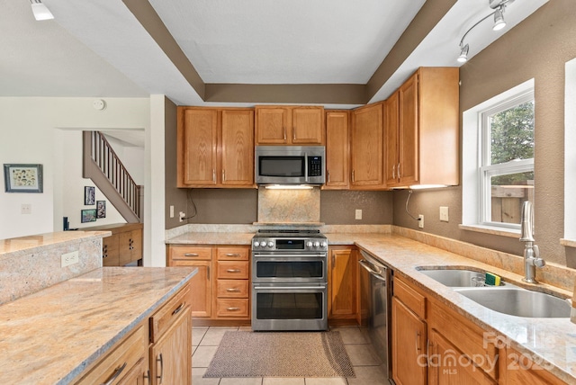 kitchen featuring decorative backsplash, a sink, stainless steel appliances, and light tile patterned floors