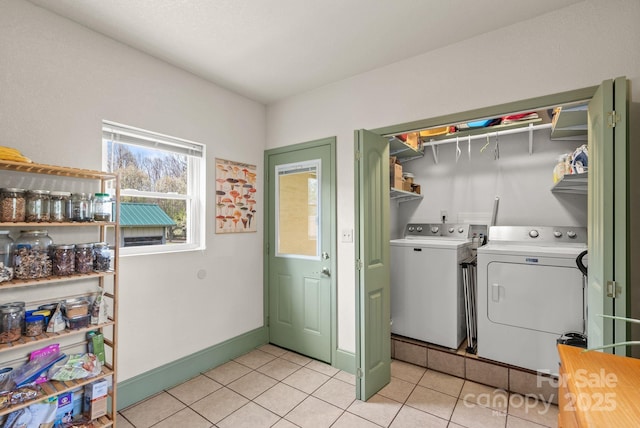 laundry room with washing machine and clothes dryer, light tile patterned flooring, baseboards, and laundry area