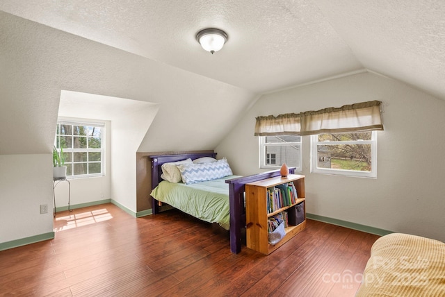 bedroom with baseboards, lofted ceiling, wood finished floors, and a textured ceiling