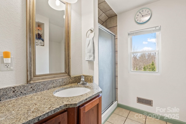 full bathroom featuring tile patterned floors, vanity, a shower stall, baseboards, and visible vents