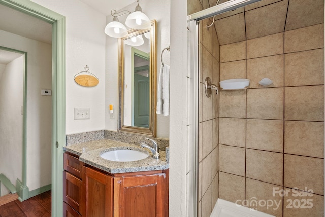 full bathroom with wood finished floors, vanity, and a shower stall