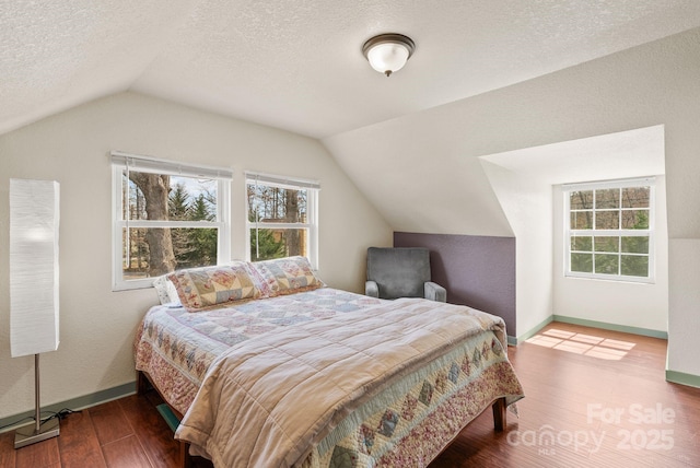 bedroom with baseboards, lofted ceiling, wood finished floors, and a textured ceiling