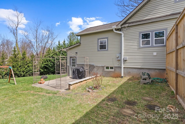 back of property featuring a lawn, a shingled roof, a patio, and a playground