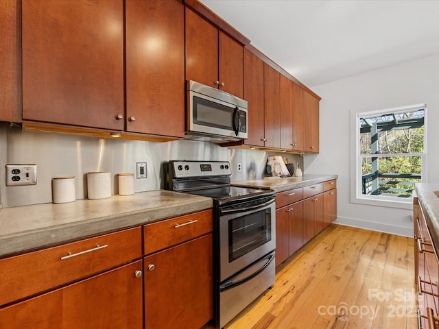 kitchen with light wood-style floors, appliances with stainless steel finishes, and brown cabinetry