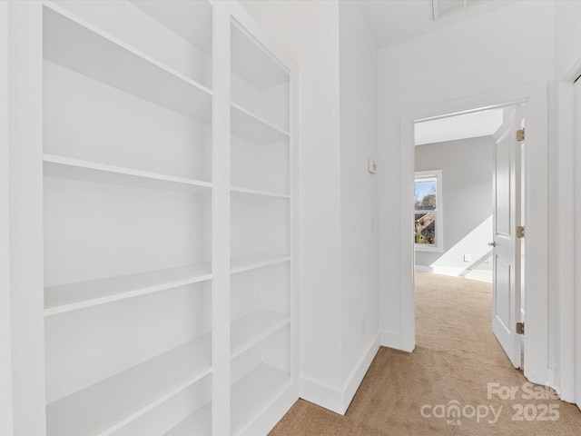corridor featuring carpet floors, baseboards, and visible vents