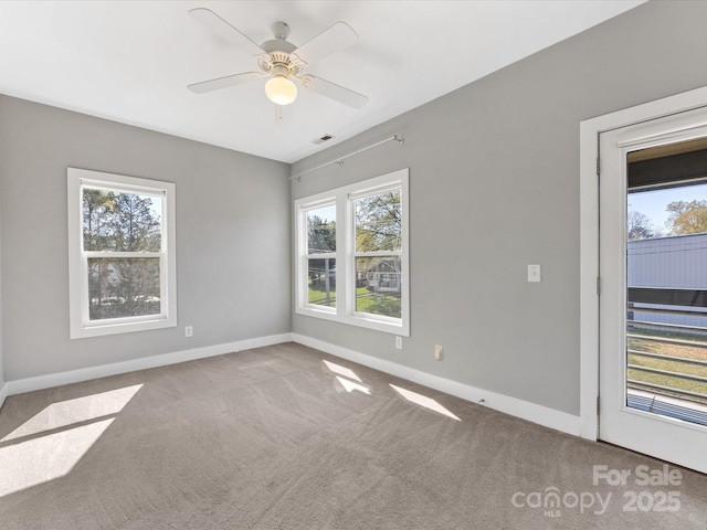 spare room featuring baseboards, carpet flooring, a ceiling fan, and a wealth of natural light