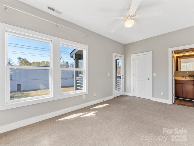 interior space with connected bathroom, carpet, a ceiling fan, baseboards, and visible vents