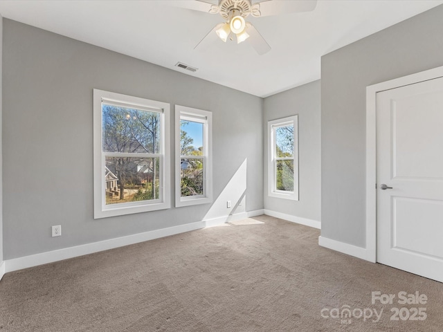 carpeted spare room featuring a ceiling fan, baseboards, and visible vents