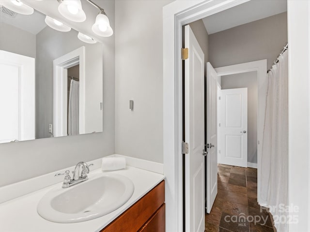 full bathroom featuring stone tile floors, visible vents, and vanity