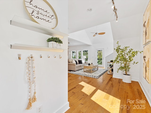 foyer entrance featuring ceiling fan, track lighting, high vaulted ceiling, baseboards, and light wood finished floors