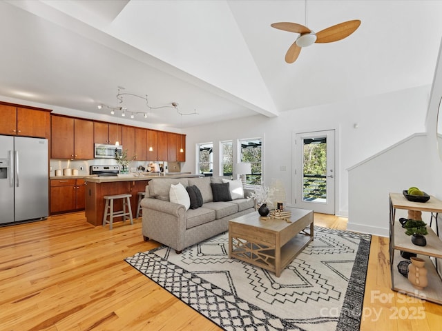 living room featuring light wood finished floors, ceiling fan, and high vaulted ceiling