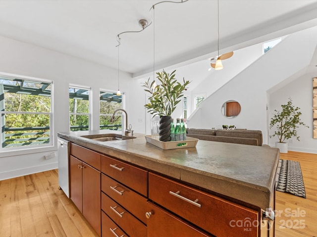 kitchen with a sink, baseboards, stainless steel dishwasher, and light wood finished floors