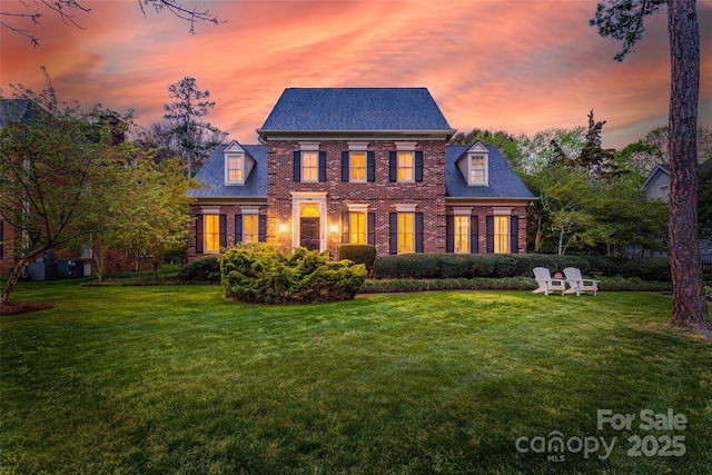 colonial inspired home featuring a front lawn and brick siding