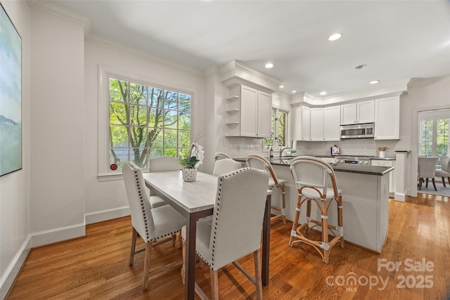 dining area featuring crown molding, baseboards, and light wood-type flooring