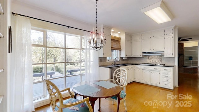 116 Jonas Dr, Lincolnton, NC 28092 - kitchen with stainless steel gas stovetop, decorative backsplash, dark countertops, a sink, and a notable chandelier