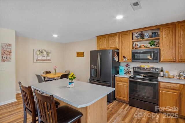 12 Hutchinson Woods Dr, Fletcher, NC 28732 - kitchen featuring black electric range oven, open shelves, light wood-style floors, a kitchen bar, and refrigerator with ice dispenser