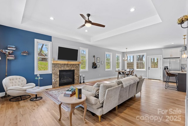 209 Fall Leaves Dr, Fairview, NC 28730 - living room featuring light wood finished floors, ceiling fan, a tray ceiling, a fireplace, and recessed lighting