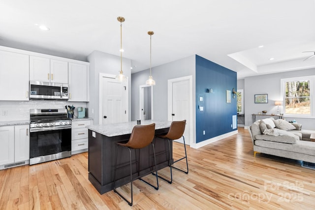 209 Fall Leaves Dr, Fairview, NC 28730 - kitchen with appliances with stainless steel finishes, open floor plan, light wood finished floors, tasteful backsplash, and white cabinetry