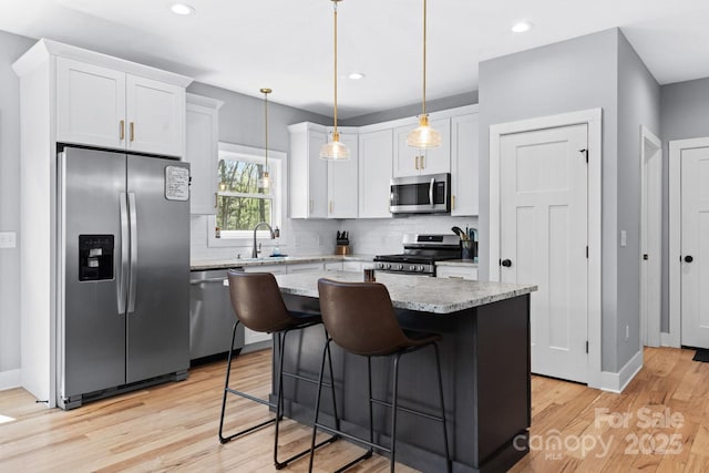 209 Fall Leaves Dr, Fairview, NC 28730 - kitchen with stainless steel appliances, decorative backsplash, light wood finished floors, white cabinets, and a center island