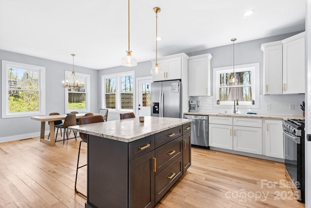 209 Fall Leaves Dr, Fairview, NC 28730 - kitchen with stainless steel appliances, a kitchen bar, white cabinetry, light wood-type flooring, and recessed lighting