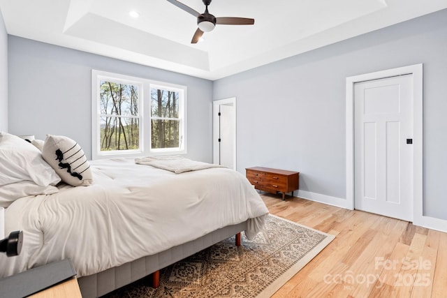 209 Fall Leaves Dr, Fairview, NC 28730 - bedroom with a tray ceiling, light wood-type flooring, and a ceiling fan