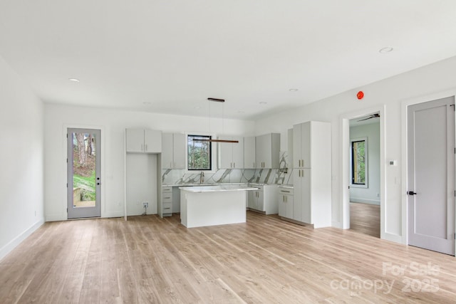 kitchen with a kitchen island, decorative backsplash, light wood finished floors, and light countertops