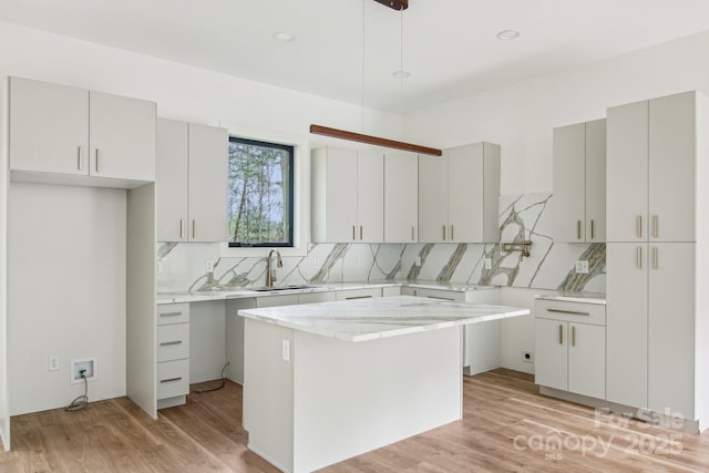 kitchen featuring light wood-type flooring, a sink, and backsplash