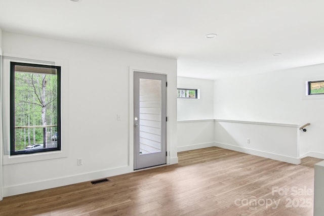 unfurnished room featuring baseboards, visible vents, and wood finished floors