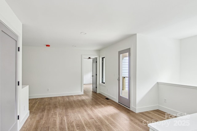 interior space with light wood-style floors, baseboards, and visible vents