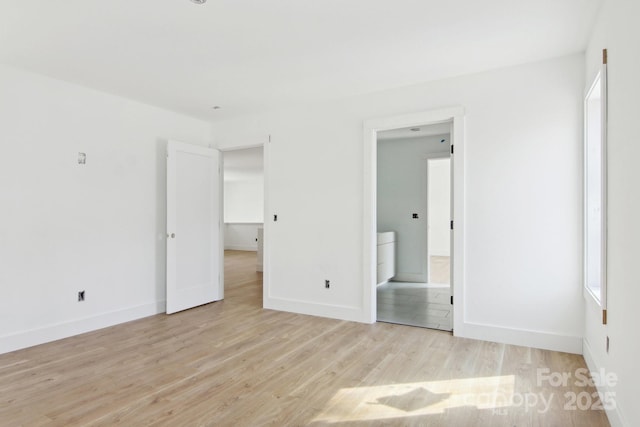 unfurnished bedroom with connected bathroom, baseboards, and light wood finished floors
