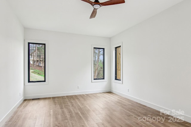 spare room with baseboards, ceiling fan, and light wood-style flooring