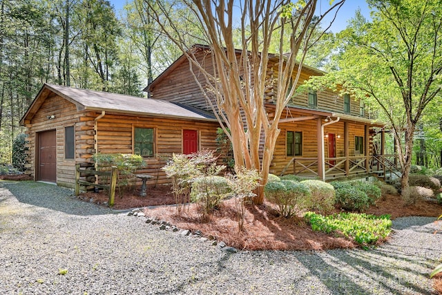 log home with covered porch, driveway, and log siding